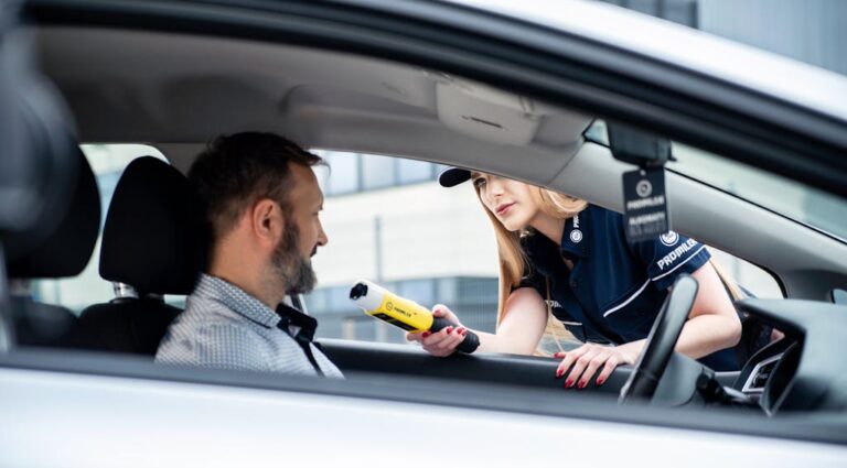 A police officer conducts a breathalyzer test on a male driver during a road safety check