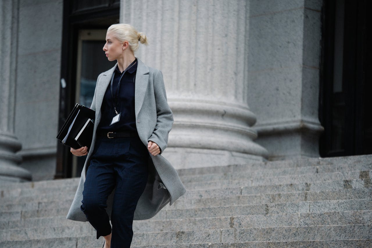 Confident woman with folders near courthouse